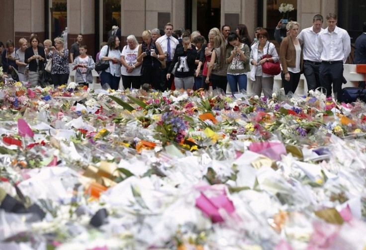 Three unidentified relatives (3rd R-R) of Sydney cafe siege victim, lawyer Katrina Dawson, gather after laying a floral tribute to her in Martin Place December 18, 2014. Australian Prime Minister Tony Abbott on Wednesday ordered a sweeping investigation i