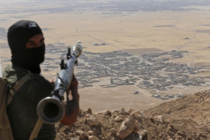 A Kurdish Peshmerga fighter holds a a rocket-propelled grenade launcher as he takes up position in an area overlooking Baretle village (background), which is controlled by the Islamic State, in Khazir, on the edge of Mosul September 8, 2014. The Kurdish f