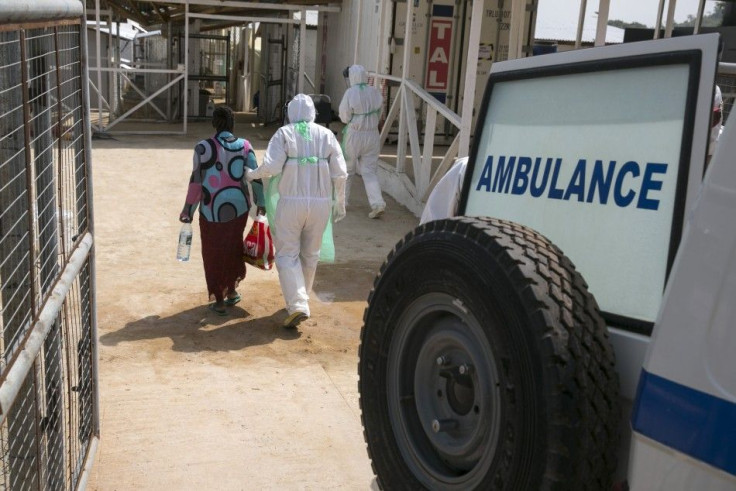 A health worker escorts a newly admitted Ebola patient in to the Kerry town Ebola treatment centre outside Freetown December 22, 2014.  REUTERS/Baz Ratner