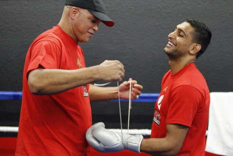 British boxer Amir Khan (R) laughs at a comment from an onlooker as his trainer Virgil Hunter (L) laces up his gloves during a media opportunity at Ponce De Leon Boxing Club in Montebello, California December 11, 2012, for his upcoming WBC silver super li