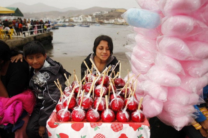A girl sells caramel apples during Saint Peter and Saint Paul&#039;s Day celebrations on Pucusana beach in Lima June 29, 2010. REUTERS/Pilar Olivares
