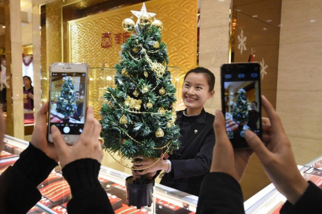 An employee poses for photographs with a Christmas tree decorated with gold accessories, as a promotional campaign of a gold store ahead of the Christmas, in Taiyuan, Shanxi province December 22, 2014. According to the store, about two kilograms (4.4 lbs)