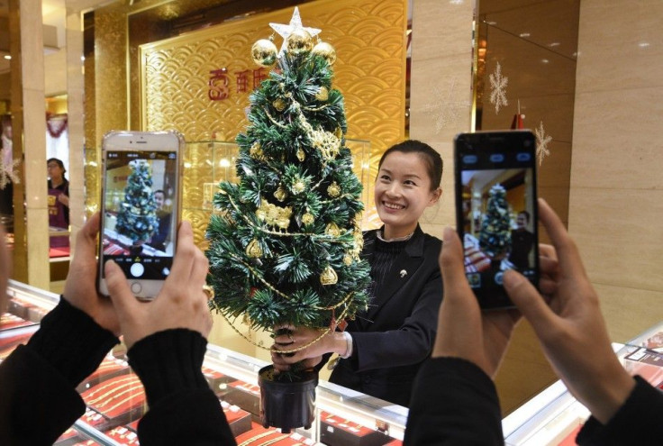 An employee poses for photographs with a Christmas tree decorated with gold accessories, as a promotional campaign of a gold store ahead of the Christmas, in Taiyuan, Shanxi province December 22, 2014. According to the store, about two kilograms (4.4 lbs)