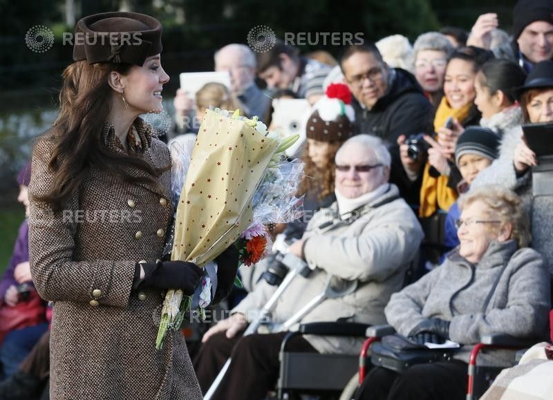 Britains Catherine, Duchess of Cambridge carries flowers as she leaves a Christmas Day morning service 