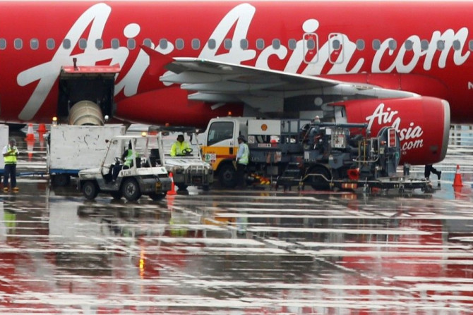 Staff members unload AirAsia&#039;s QZ8501 from Surabaya to Singapore, which took the same code as the missing plane that took off 24 hours earlier