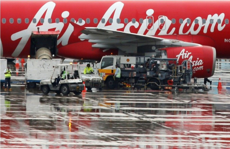 Staff members unload AirAsia&#039;s QZ8501 from Surabaya to Singapore, which took the same code as the missing plane that took off 24 hours earlier