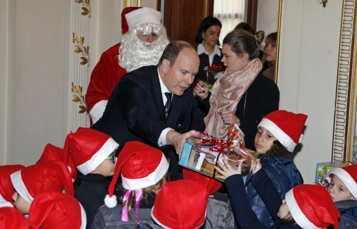 Prince Albert II of Monaco (C) distributes gifts to Monaco's children beside a Santa Claus and Camille Gottlieb (R), daughter of Princess Stephanie of Monaco, during the traditional Christmas tree ceremony at the Monaco Palace as part of Christmas holiday