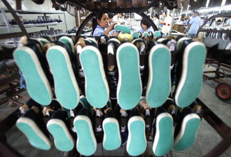 A woman hangs shoes on a shelf at a shoe factory in Hanoi November 13, 2014.