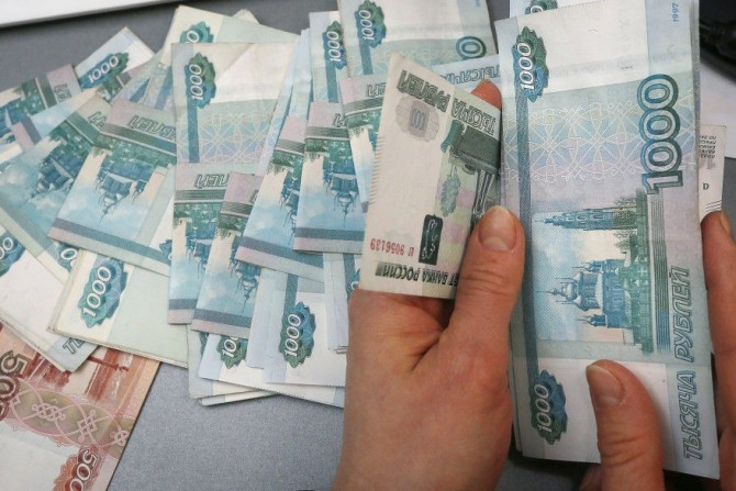 An employee counts Russian rouble banknotes