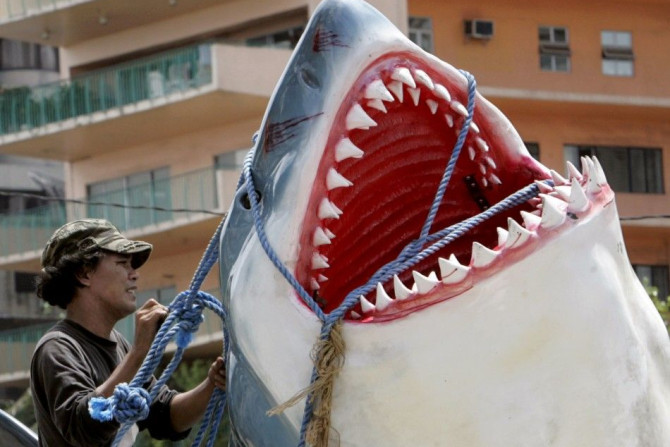 A worker ties a fiberglass replica of a Great White shark onto a van in Manila
