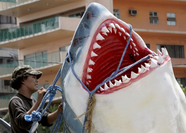A worker ties a fiberglass replica of a Great White shark onto a van in Manila
