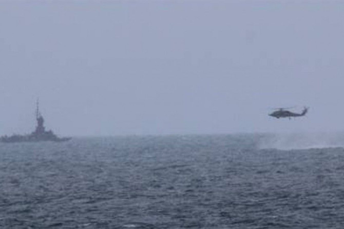 An MH-60R helicopter, attached to the USS Sampson (DDG 102), approaches an Indonesian patrol vessel