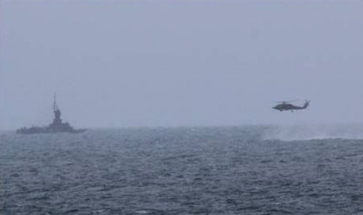 An MH-60R helicopter, attached to the USS Sampson (DDG 102), approaches an Indonesian patrol vessel