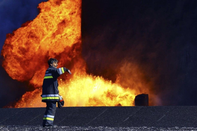 A firefighter stands near the fire of a storage oil tank at the port of Es Sider in Ras Lanuf