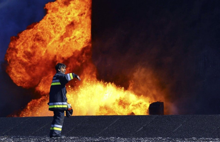 A firefighter stands near the fire of a storage oil tank at the port of Es Sider in Ras Lanuf