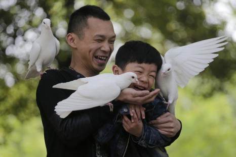 People play with pigeons at a park in Wuhan, Hubei province, April 10, 2013.