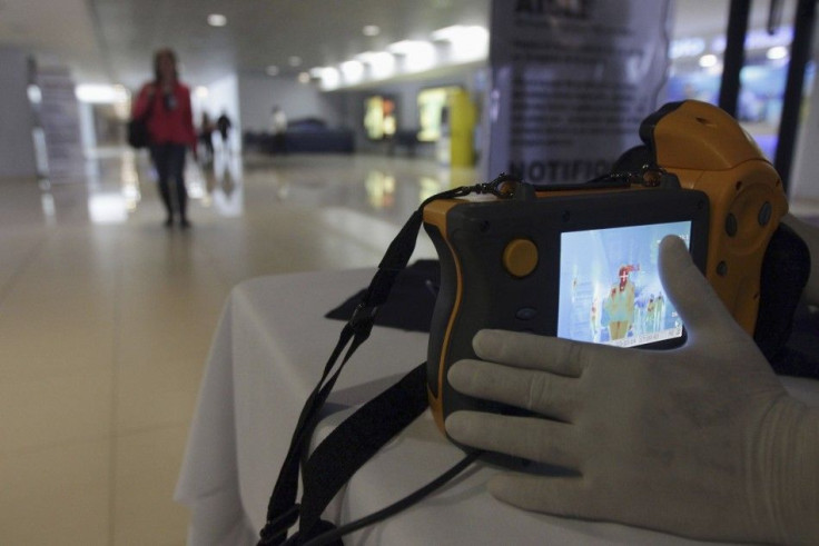 A health worker uses an infrared scanner to scan the temperatures of passengers arriving at the international airport in Guatemala City October 13, 2014. Guatemala has stepped up caution and security measures at the airport to prevent an Ebola outbreak, a