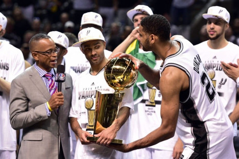 San Antonio Spurs forward Tim Duncan takes the Larry O&#039;Brian Trophy from guard Tony Parker as he does a TV interview with ESPN announcer Stuart Scott