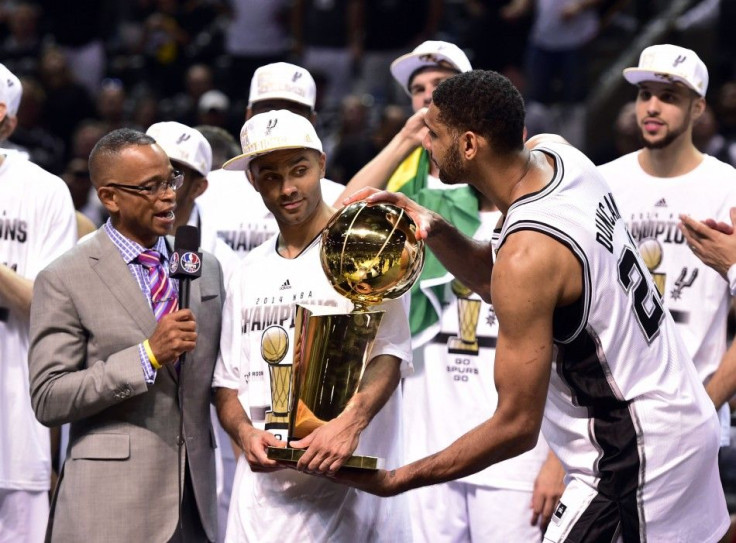 San Antonio Spurs forward Tim Duncan takes the Larry O&#039;Brian Trophy from guard Tony Parker as he does a TV interview with ESPN announcer Stuart Scott