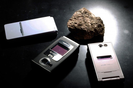 A bastnaesite mineral containing rare earth from the United States, is pictured next to cell phones, which utilises the minerals during manufacturing at a laboratory of Yasuhiro Kato, an associate professor of earth science at the University of Tokyo, in 