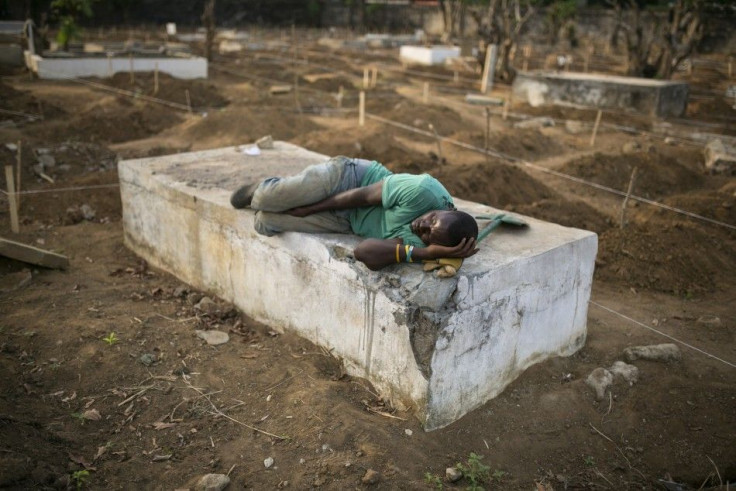 A grave digger sleeps near the graves of Ebola victims at a cemetery in Freetown, December 17, 2014.  The death toll in the Ebola epidemic has risen to 6,915 out of 18,603 cases as of Dec. 14, the World Health Organization (WHO) said on Wednesday. There a