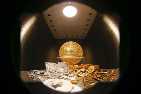 Gold and silver bars and coins are stacked on a table in the safe deposit boxes room of the ProAurum gold house in Munich March 3, 2014. The rising threat of war between Ukraine and Russia sent investors scurrying for relative safety on Monday, pushing st