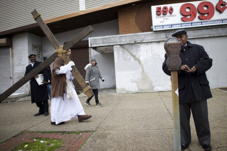 A man puts change into a parking meter as Michael Grant, 28, &quot;Philly Jesus,&quot; carries a 12 foot cross 8 miles through North Philadelphia to LOVE Park in Center City as part of a Christmas walk to spread the true message of the holiday in Philadel