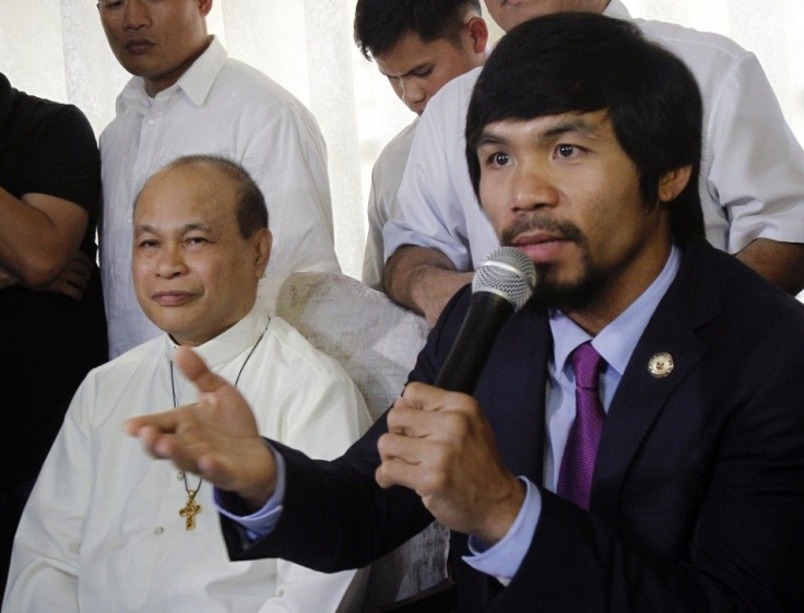 WBO welterweight champion and congressman Manny &quot;Pacman&quot; Pacquiao speaks as President of the Catholic Bishops Conference of the Philippines (CBCP), Bishop Nereo Odchimar, looks on during a news conference at the CBCP in Manila May 17, 2011. A se