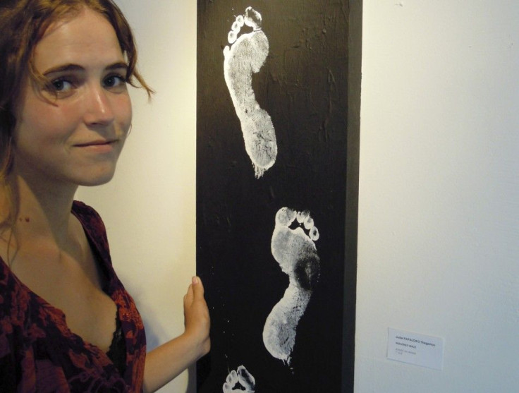 Morgan Wienberg, 22, poses beside a painting of footprints at the Jacmel Gallery in Miami