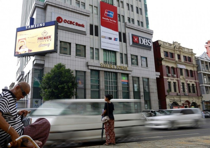 Traffic travels past signs of OCBC and DBS banks at Sakura tower in Yangon October 3, 2014. Myanmar has thrown open the door to foreign banks, but weak credit protection and tight restrictions on lending mean it's not a warm welcome, at least not yet. To 