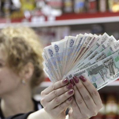 A cashier demonstrates Russian rouble banknotes taken from a cash register at a local grocery store in Stavropol, southern Russia