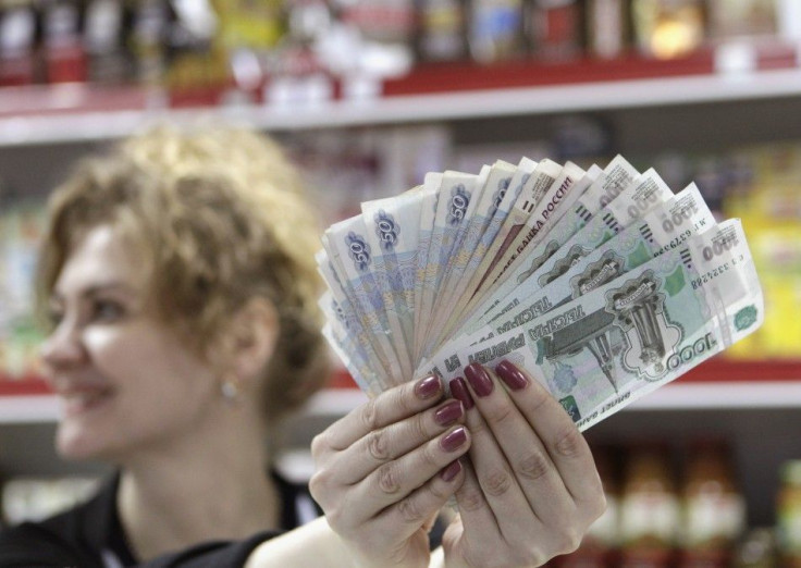 A cashier demonstrates Russian rouble banknotes taken from a cash register at a local grocery store in Stavropol, southern Russia