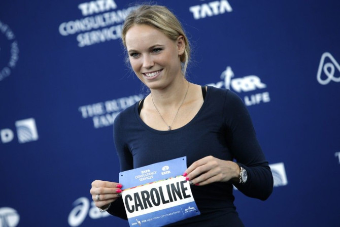 Tennis star Caroline Wozniacki of Denmark poses for photographers as she holds her race bib at a news conference to promote running in the New York City Marathon as an ambassador for the Team For Kids charity in New York, October 29, 2014. Wozniacki will 