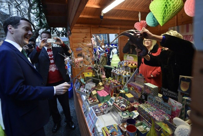 Britain's Chancellor of the Exchequer George Osborne (L) examines a children's toy at market stalls promoting the livelihoods of small business owners at Downing Street in London, December 5, 2014.