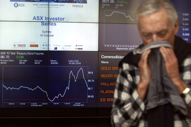 An investor wipes his face as he stands in the Australian Securities Exchange in front of boards displaying stock prices in central Sydney October 16, 2014. Australian shares slid 1.1 percent on Thursday after U.S. stocks lost ground as investors continue
