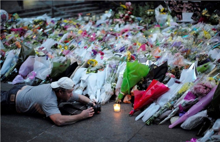 A visitor to the makeshift memorial to the victims of the Sydney cafe siege takes a close-up picture of a candle among flowers
