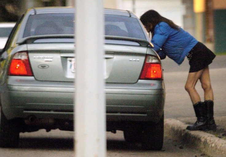 A woman leans into the window of a passing car just before getting into it near the infamous 118 Avenue in Edmonton