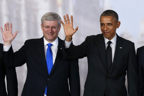 Canada's Prime Minister Stephen Harper (L) and U.S. President Barack Obama wave while taking a family photo at the G7 summit in Brussels June 5, 2014. REUTERS/Kevin Lamarque