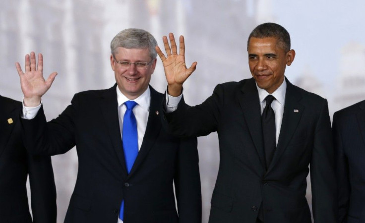 Canada's Prime Minister Stephen Harper (L) and U.S. President Barack Obama wave while taking a family photo at the G7 summit in Brussels June 5, 2014. REUTERS/Kevin Lamarque