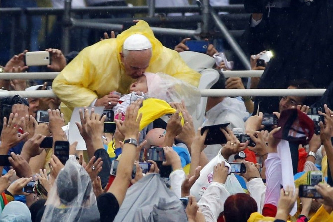 Pope Francis kisses a child as he arrives to lead an open-air Mass at Rizal Park in Manila January 18, 2015. REUTERS/Stefano Rellandini