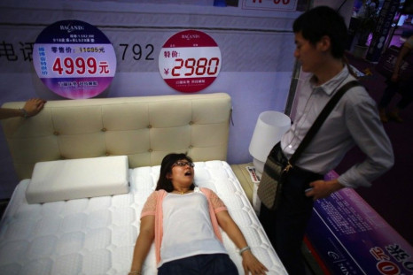 A woman lies on a bed as she talks to her partner at a furniture stand during a wedding exhibition in downtown Shanghai June 16, 2013. As couples celebrate the &quot;Qixi&quot; festival on Tuesday, the Chinese equivalent of Valentine's Day, millions of wo