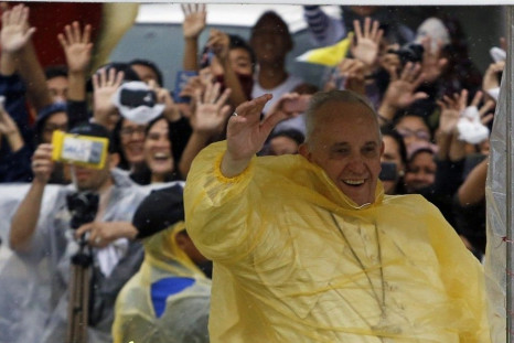 Pope Francis smiles as he waves to residents during a motorcade in Tacloban city, after holding a mass near the airport, January 17, 2015. An emotional Francis, wearing a plastic poncho over his vestments to protect him from the wind and rain on Saturday,