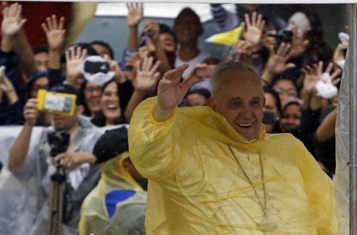 Pope Francis smiles as he waves to residents during a motorcade in Tacloban city, after holding a mass near the airport, January 17, 2015. An emotional Francis, wearing a plastic poncho over his vestments to protect him from the wind and rain on Saturday,