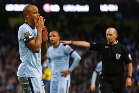 Manchester City captain Vincent Kompany (L) reacts after conceding a penalty, as referee Mike Dean points to the spot during their English Premier League soccer match against Arsenal at the Etihad stadium in Manchester, northern England January 18, 2015.