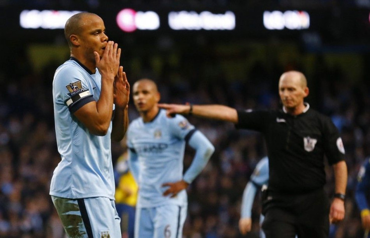 Manchester City captain Vincent Kompany (L) reacts after conceding a penalty, as referee Mike Dean points to the spot during their English Premier League soccer match against Arsenal at the Etihad stadium in Manchester, northern England January 18, 2015.