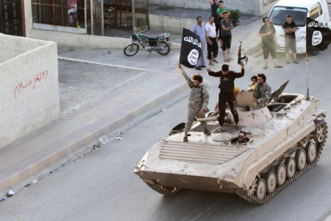 Militant Islamist fighters hold the flag of Islamic State while taking part in a military parade