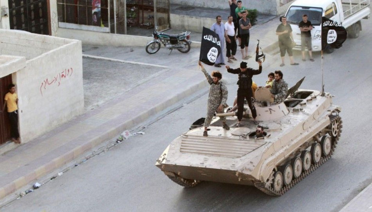 Militant Islamist fighters hold the flag of Islamic State while taking part in a military parade