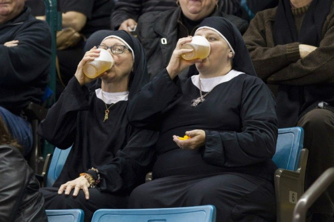 Two women wearing nun outfits drink beer