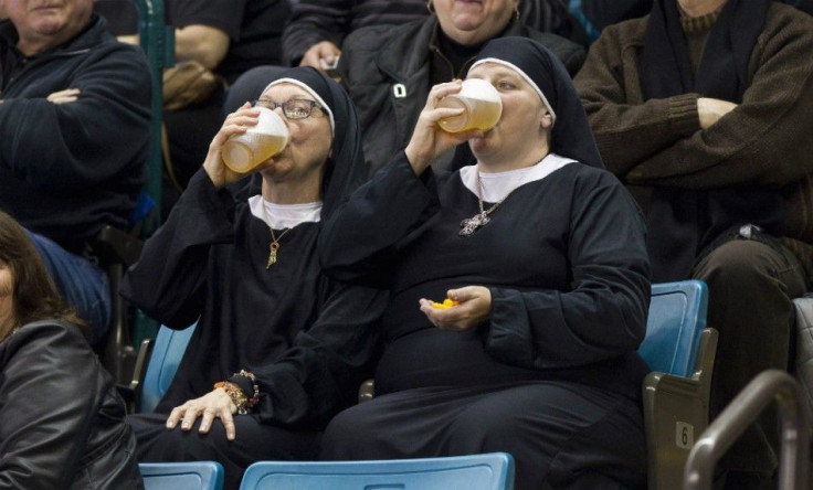 Two women wearing nun outfits drink beer