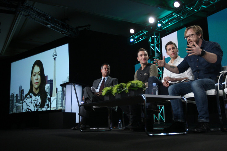 Actor Tatiana Maslany (L-R) appears on a screen as she joins senior vice president of programming Richard De Croce, actors Jordan Gevaris, Ari Millen, and co-creator, director and executive producer John Fawcett in the BBC America "Orphan Black" panel 